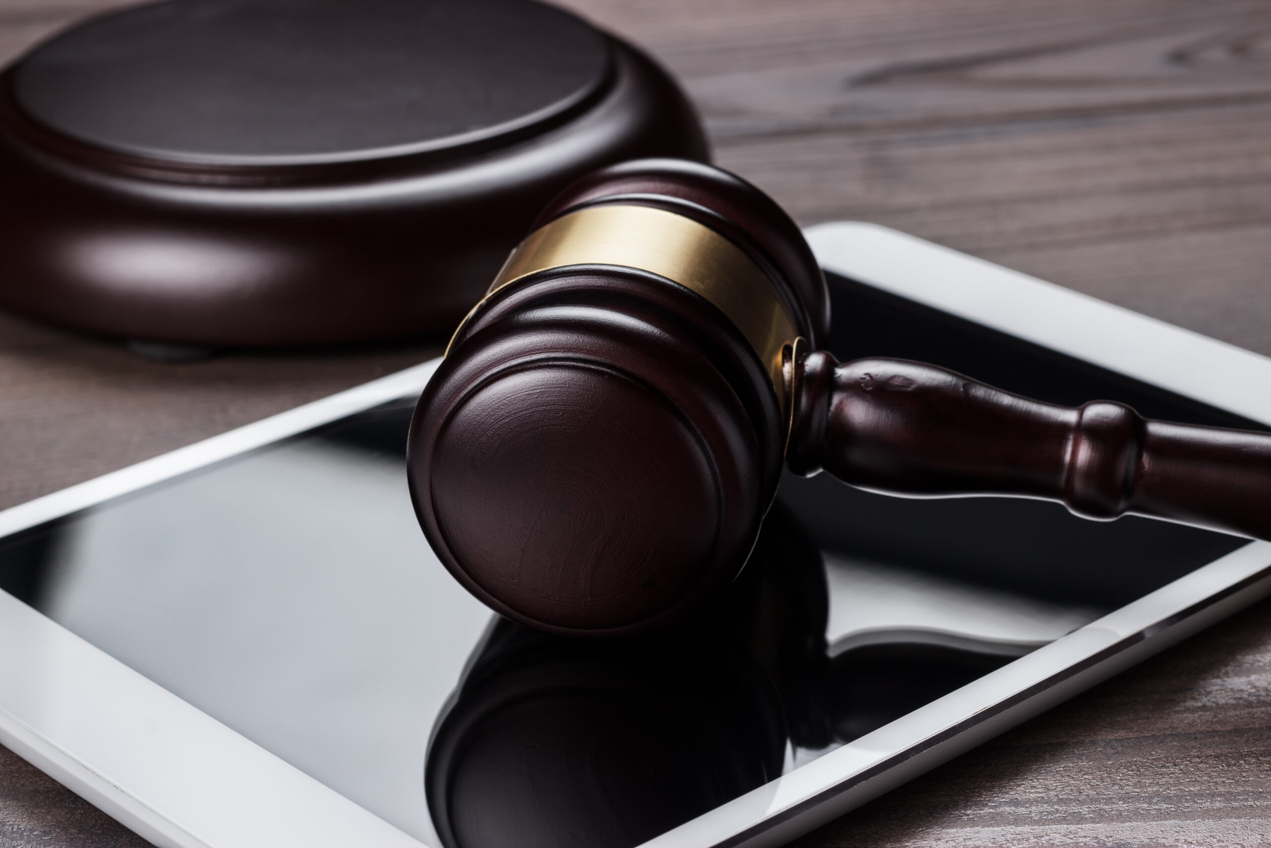 Judge’s gavel and a white tablet computer on a brown wooden table